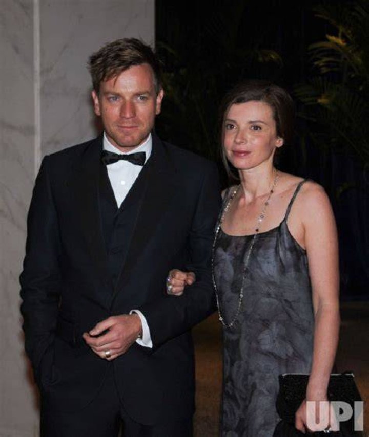 Both Ewan McGregor and Eve Mavrakis are wearing black clothes as they are side-hugging each other.