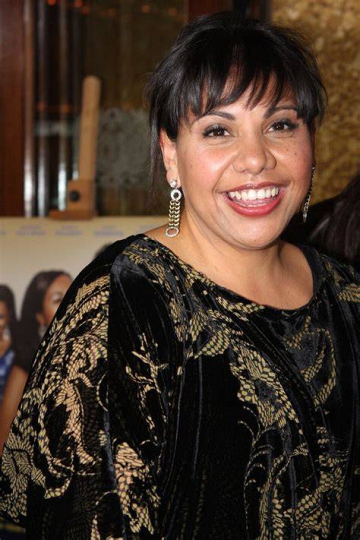 Deborah Mailman posing for a photo by wearing white dress.